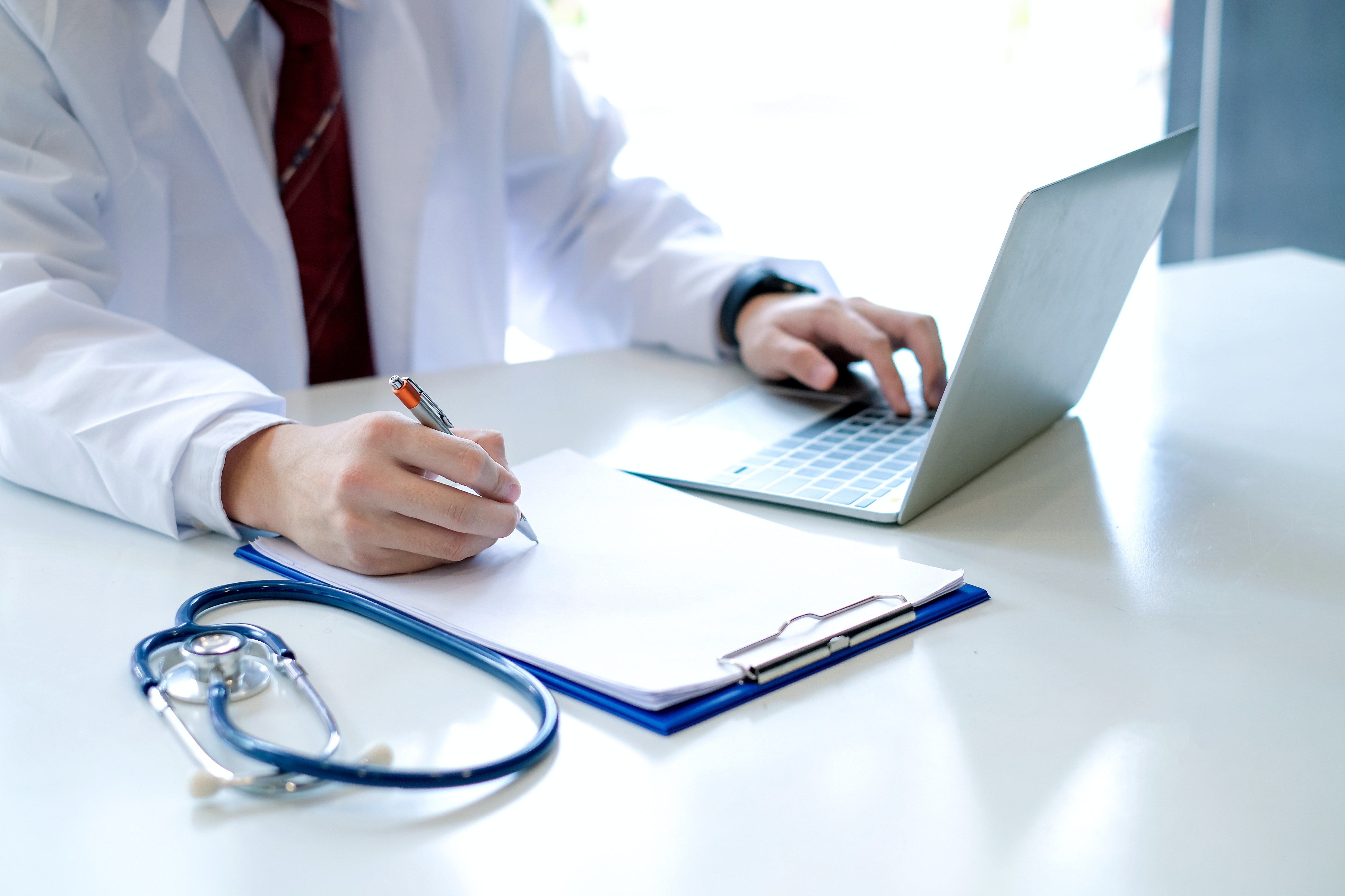 Doctor working on a document and laptop